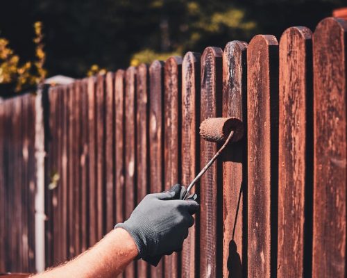 man-protective-gloves-is-painting-wooden-fence-bright-summer-day_613910-17100